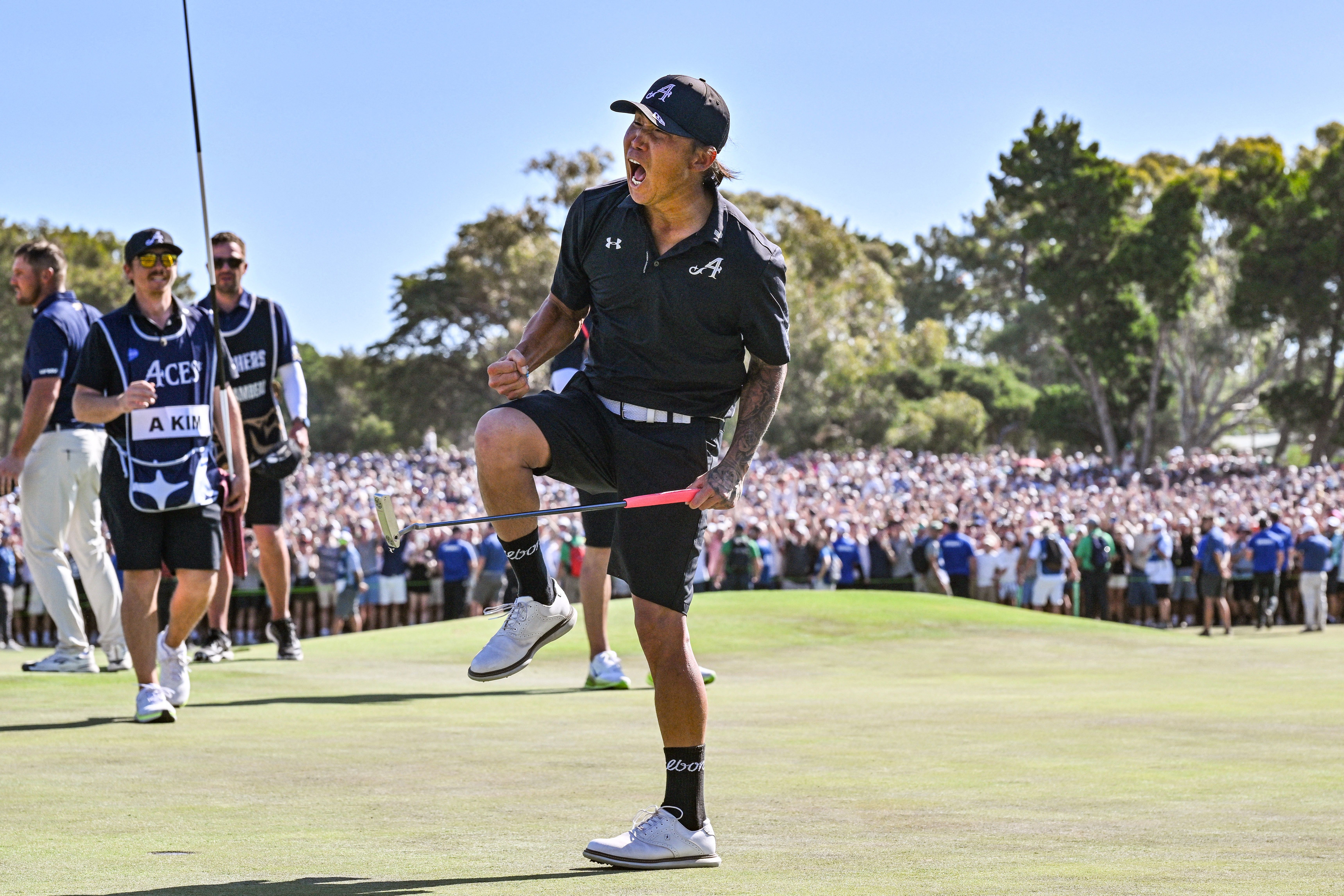Golfer celebrates on a green, raising his leg before a cheering crowd.
