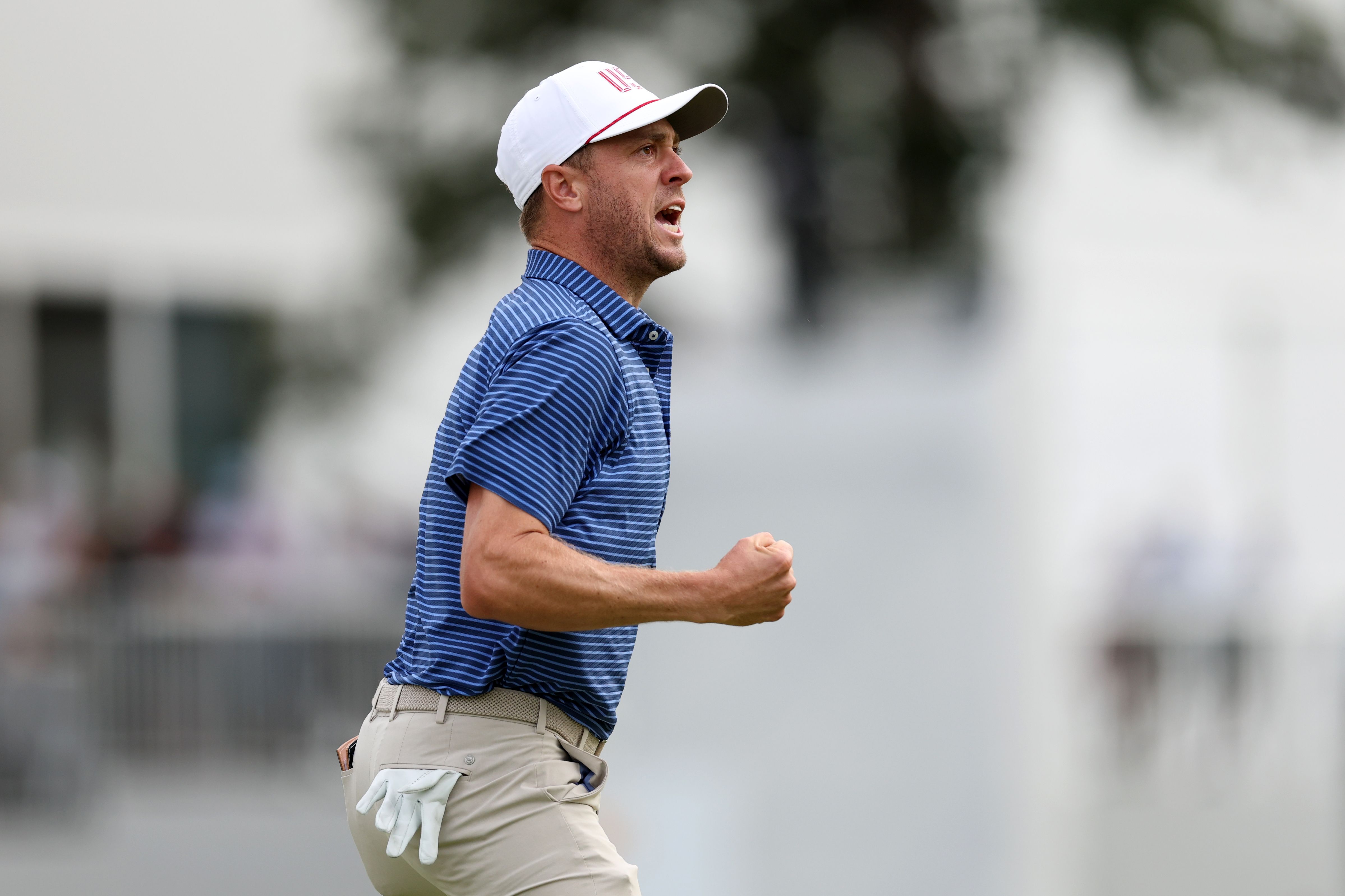 Male golfer in a blue shirt celebrates with a raised fist and open mouth.