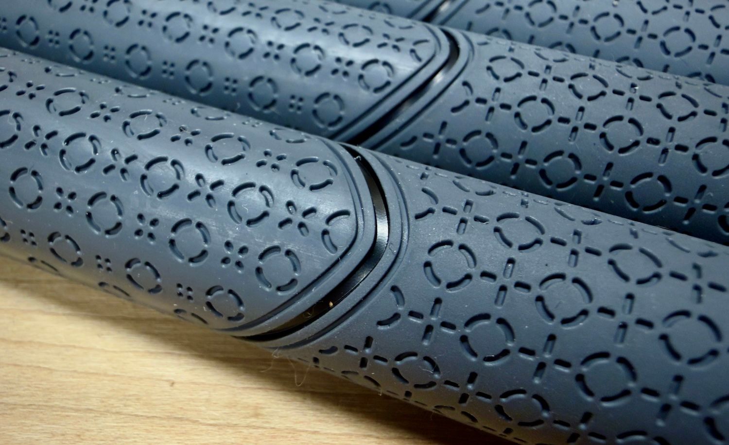Dark grey rubber mats with circular and cross patterns, neatly rolled for storage.