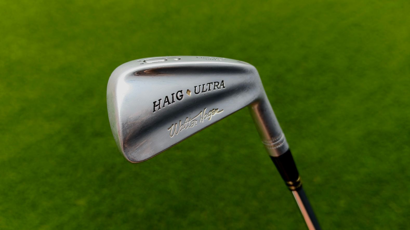 Silver MARU-SAN golf iron club head resting on green grass.