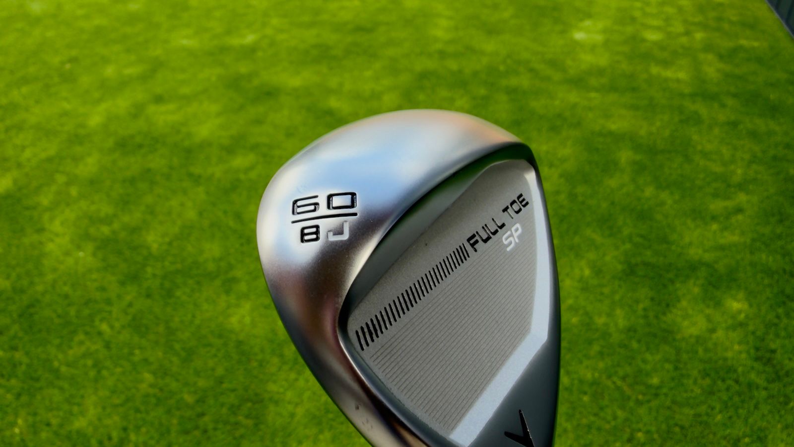 Close-up of a shiny silver golf wedge head with '60 D' engraved on its back.