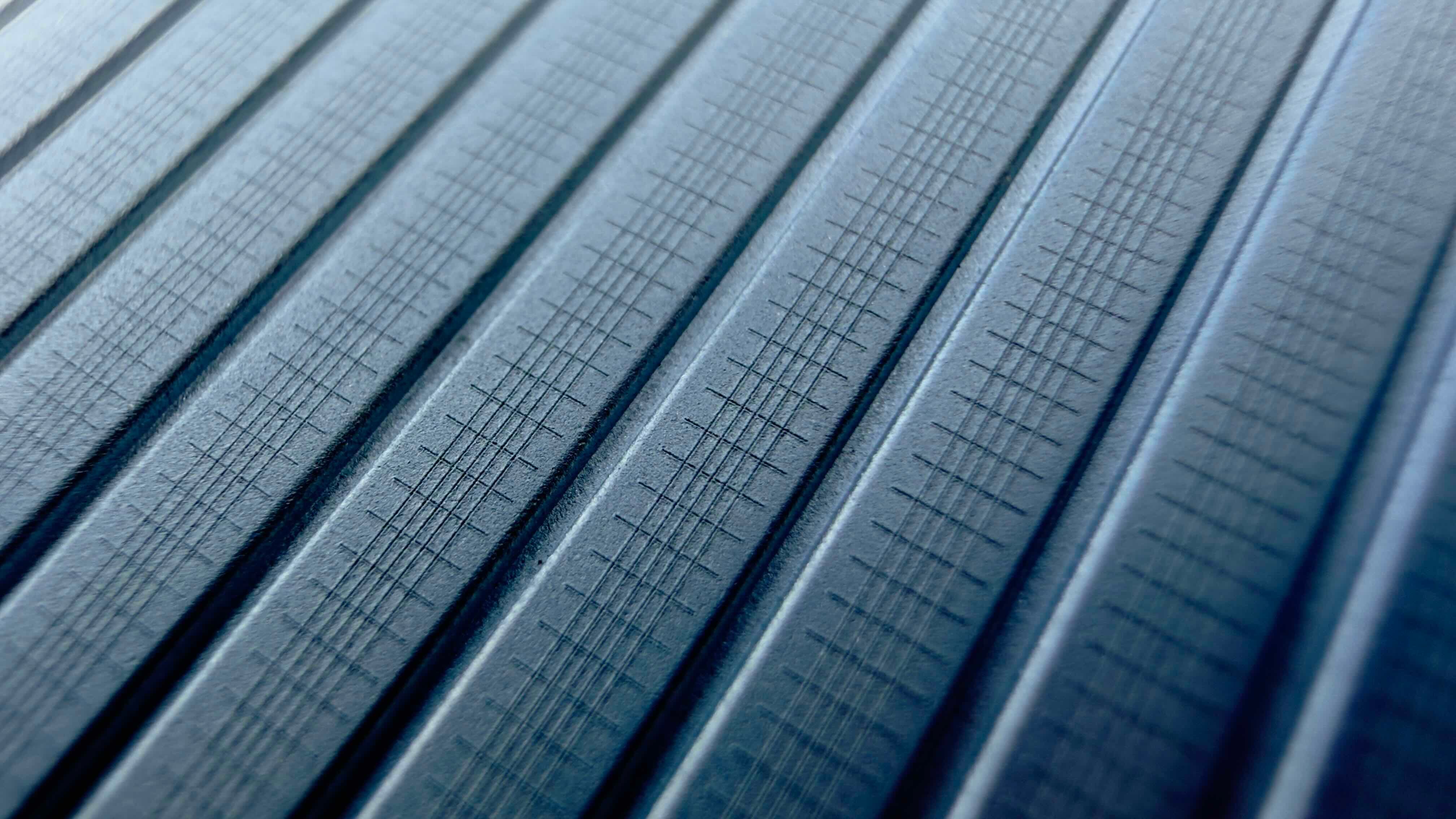 Dark gray textured surface with parallel raised lines and subtle crosshatch pattern.