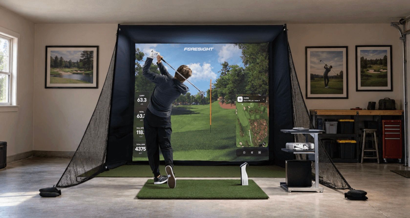 Man swings golf club in an indoor simulator setup with a large projected course.
