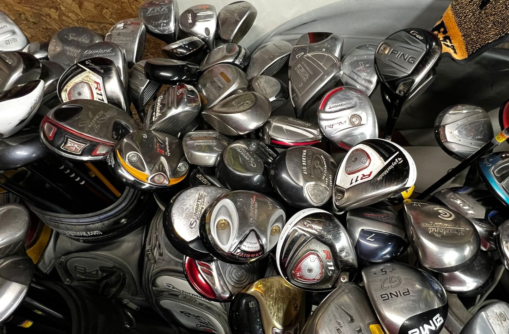 A large pile of various used golf club heads, including drivers and woods.